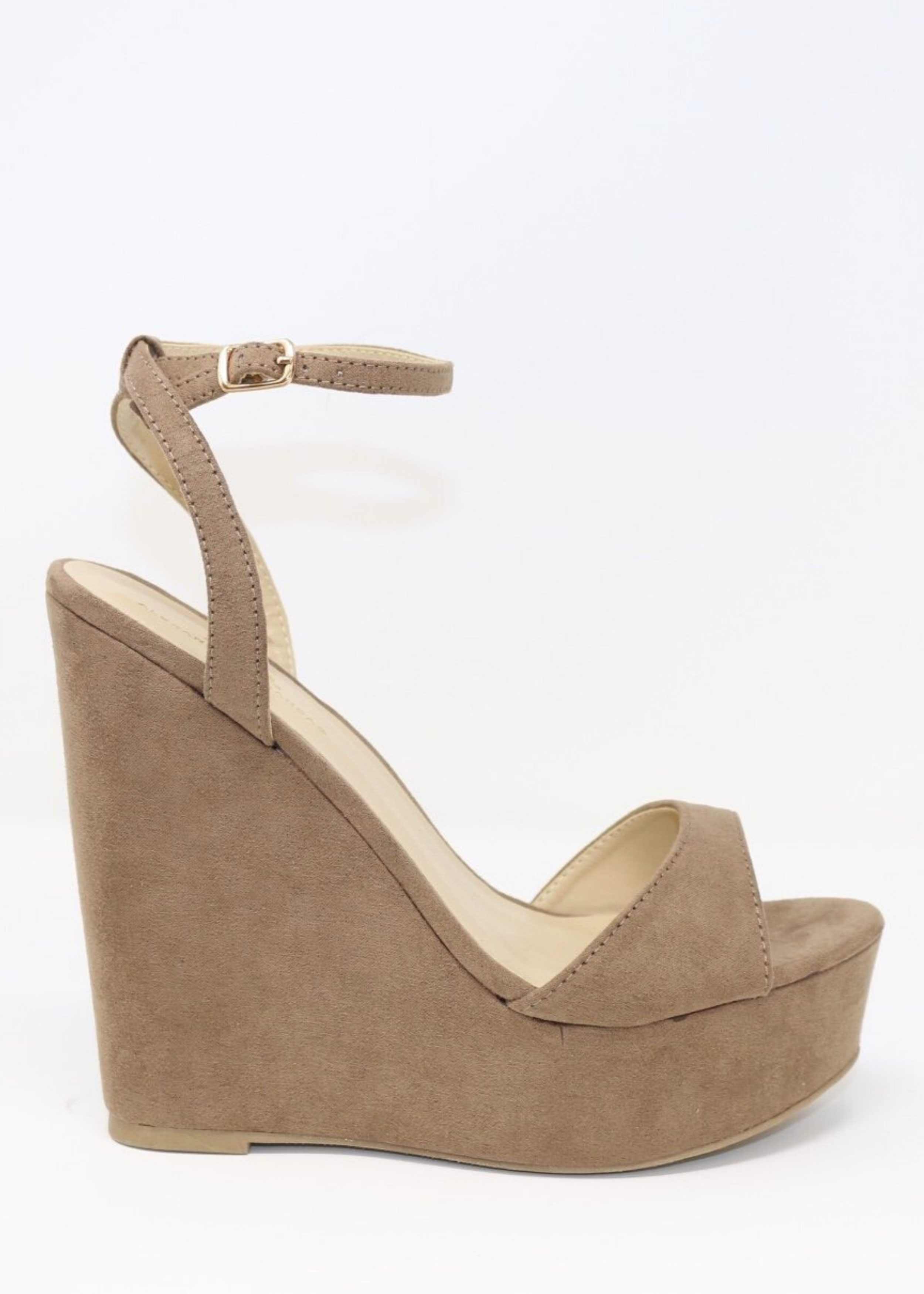 Taupe suede ALYSSA wedge with crisscross strap that crosses in the back as the buckle buckles in the side that is silver. Thick to thin back to thick strap in the front. side view as model is standing