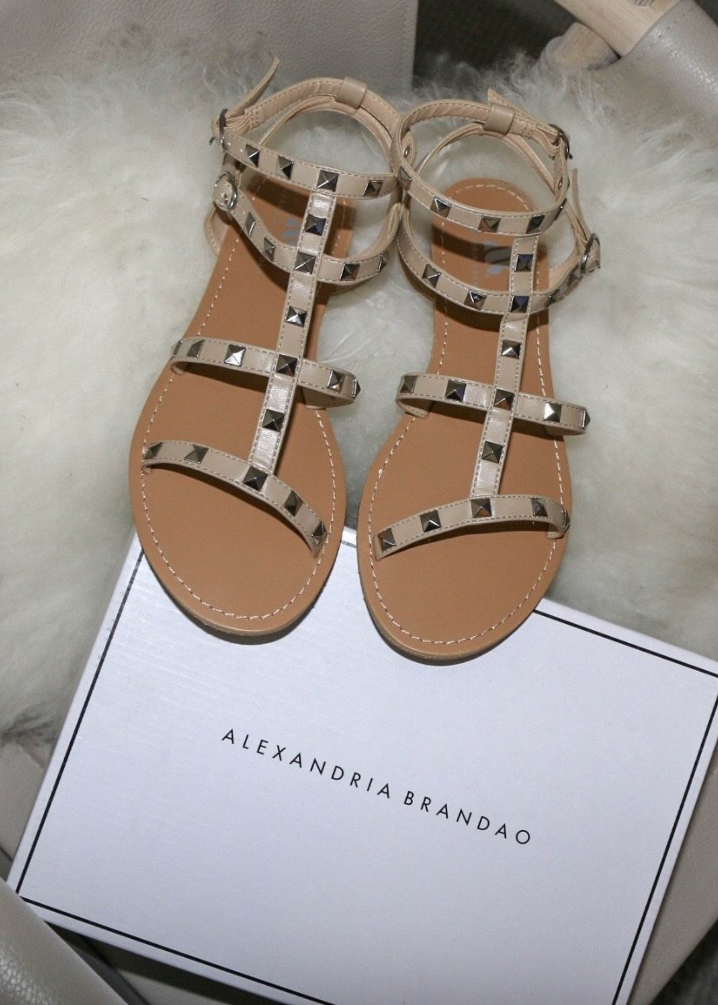 Ava sandals in Nude with Silver studded details on top of a plush fur pillow.