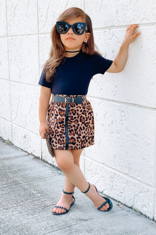 TODDLER GIRL WEARING ANIMAL PRINT SKIRT PAIRED WITH SHOES BY Alexandria Brandao BLACK JELLY STRAP SANDALS FOR KIDS AND GIRLS. MOMMY AND ME MATCHING SANDALS FOR MOMMY AND ME AND MOTHER DAUGHTER FALL OUTFITS