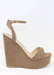 Taupe suede ALYSSA wedge with crisscross strap that crosses in the back as the buckle buckles in the side that is silver. Thick to thin back to thick strap in the front. side view as model is standing