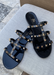 Aurora Black Jelly sandal that has  Gold Studs on all straps and is a slip on sandal.  Sandal has three equally separated horizontal straps that goes all the way to top of the bridge of the foot and one strap in the middle connecting all straps