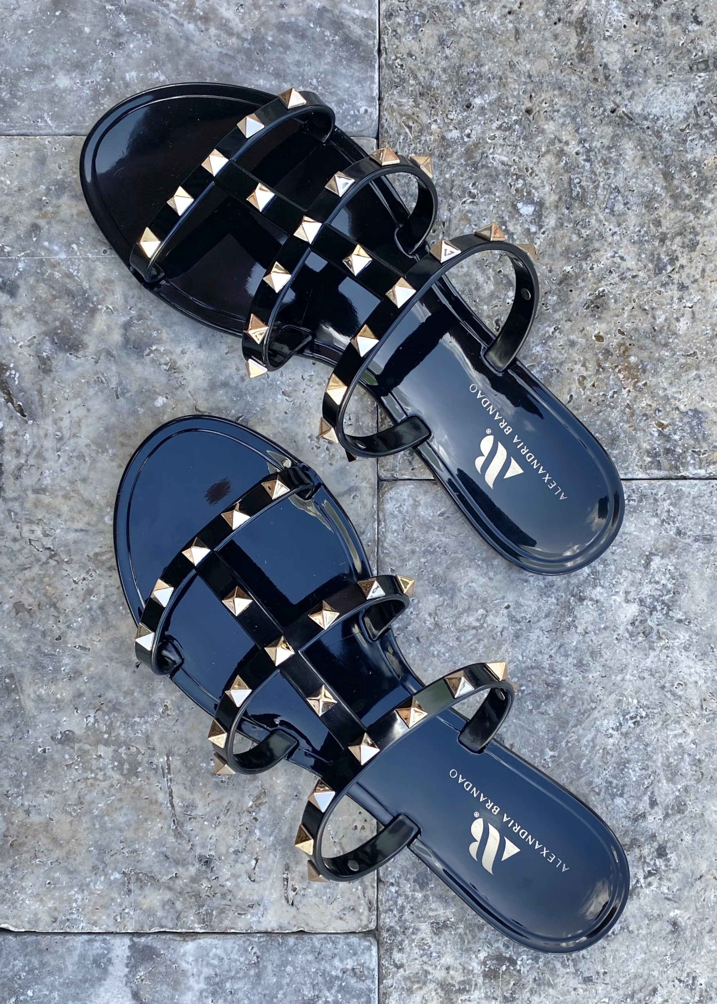 Aurora Black Jelly sandal that has  Gold Studs on all straps and is a slip on sandal.  Sandal has three equally separated horizontal straps that goes all the way to top of the bridge of the foot and one strap in the middle connecting all straps