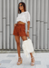@carlanunez_ styled in a white top and rusted colored shorts accessorized with Amora in nude. 