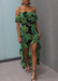 Model walking swiftly wearing a tropical green palm print dress and Aria sandals in Black.