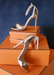 Ali sandal heels in Rose Gold propped up on Orange boxes.