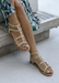 A woman's legs wearing a tropical green blue dress and Ava sandals in Nude with Gold stud details.
