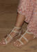 Ava gladiator sandals in Nude with Nude studded details on wood grain floor. 