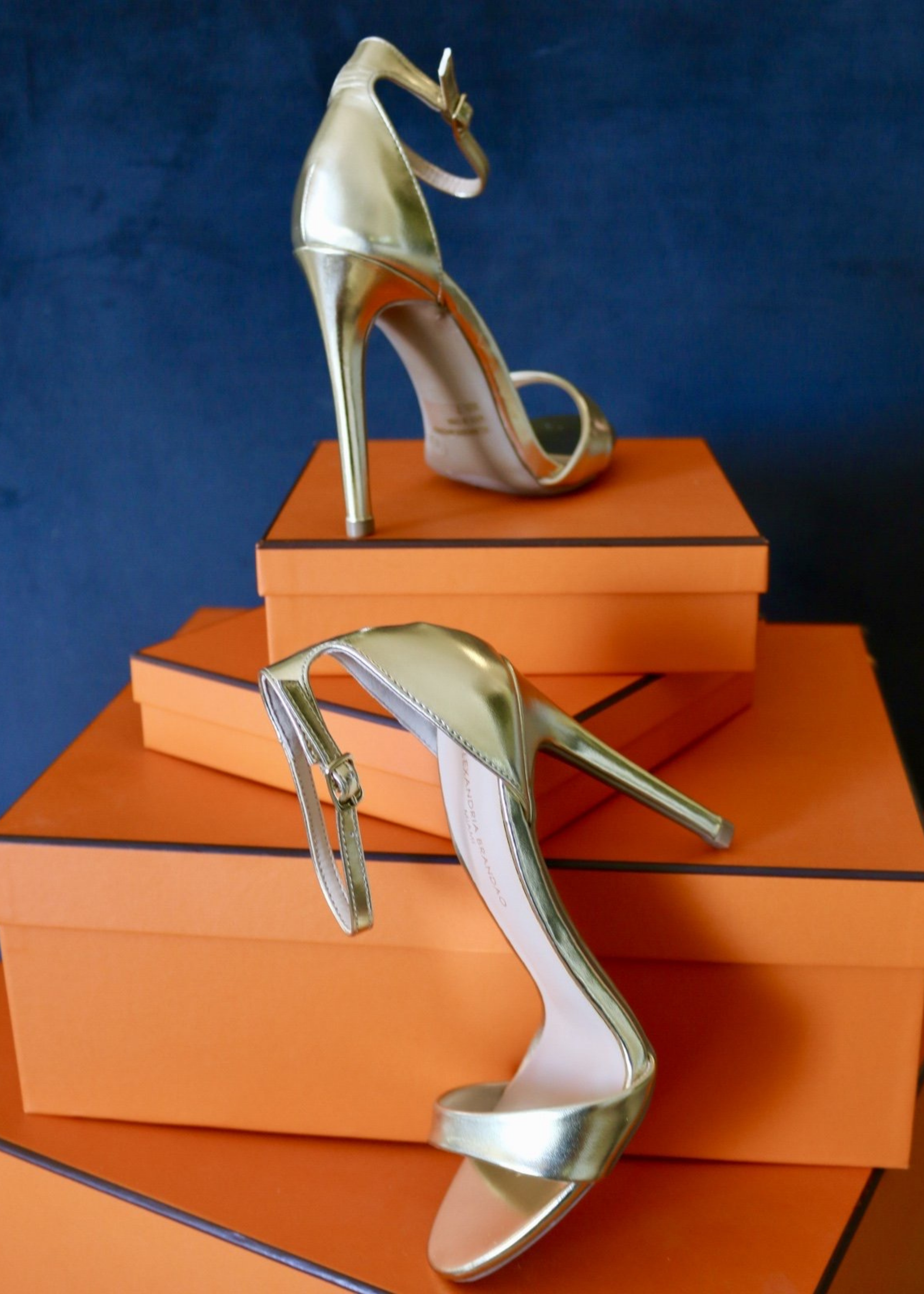 Gold Ali Heels propped up on  orange boxes. 