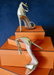 Gold Ali Heels propped up on  orange boxes. 